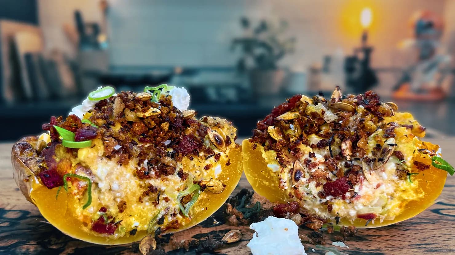 Halved stuffed squash with crispy toppings on a wooden table in a cozy kitchen. Warm lighting enhances the vibrant colors and textures.