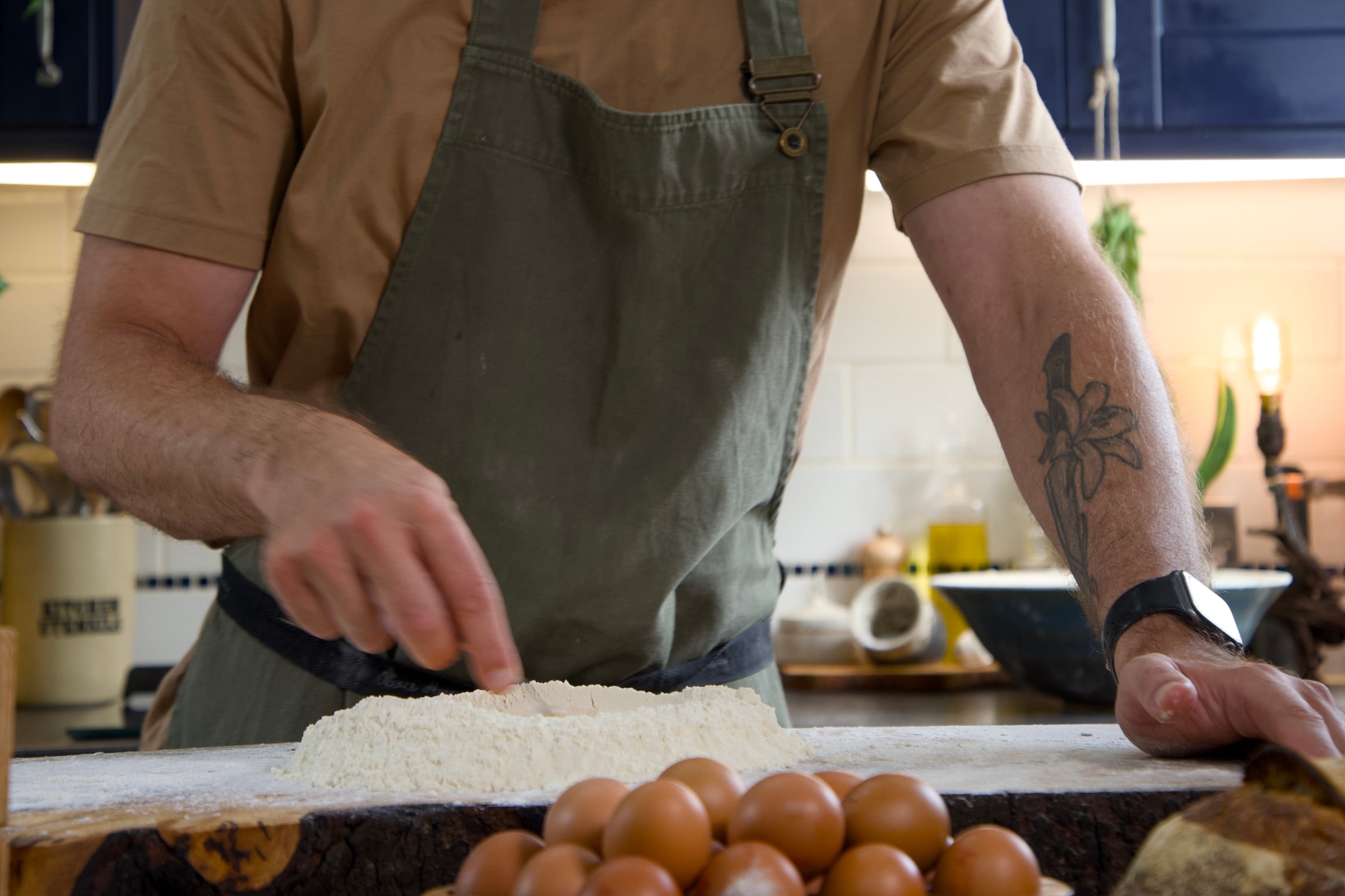Tom pressing dough out on a floured board next to a tray of eggs