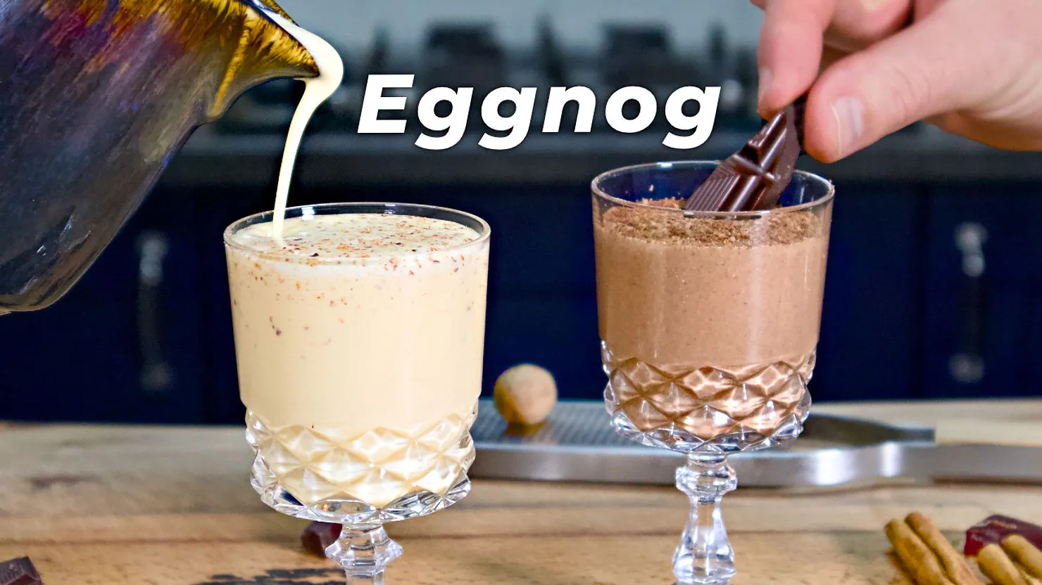 Two crystal glasses filled with creamy drinks, one eggnog being poured, and a hand placing chocolate in the other. Text: "Eggnog".