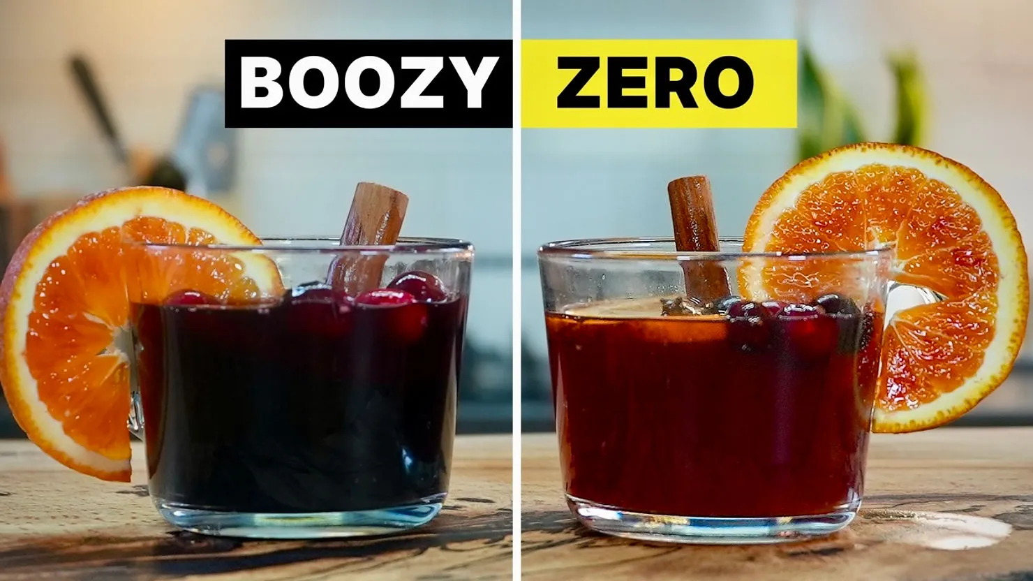 Two glasses of mulled wine on a wooden table, one labeled "BOOZY" and the other "ZERO," each with orange slices and cinnamon sticks.
